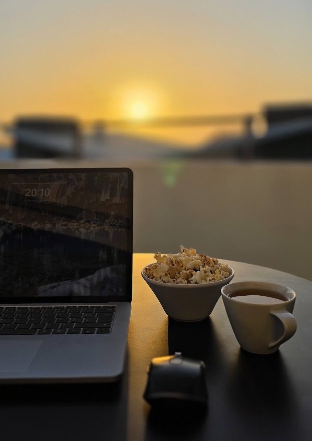 Portátil, chávena e taça numa mesa ao pôr do sol